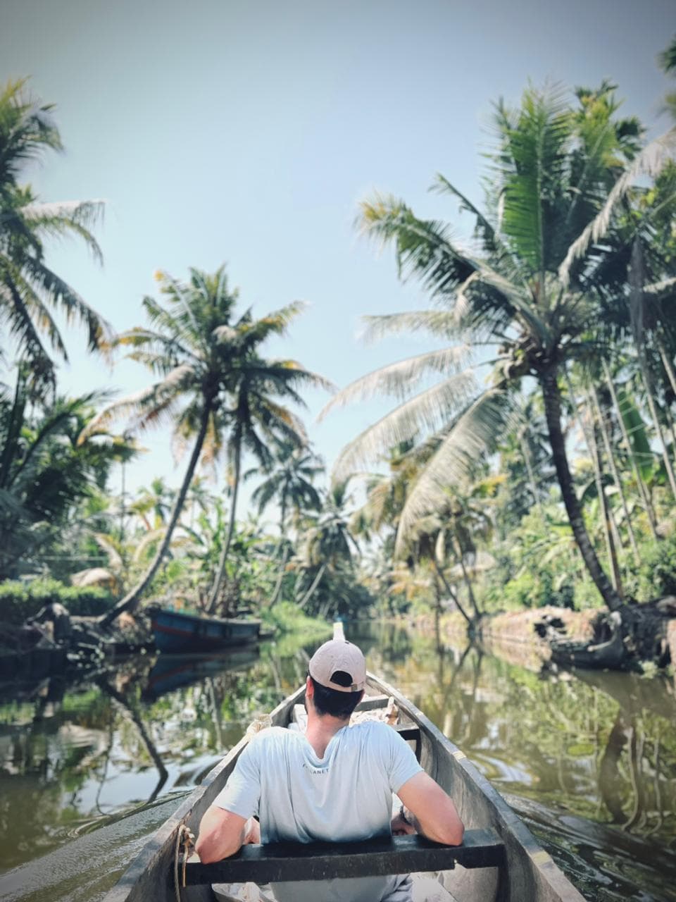 A solo guest drifting through a narrow palm-lined canal in a country boat