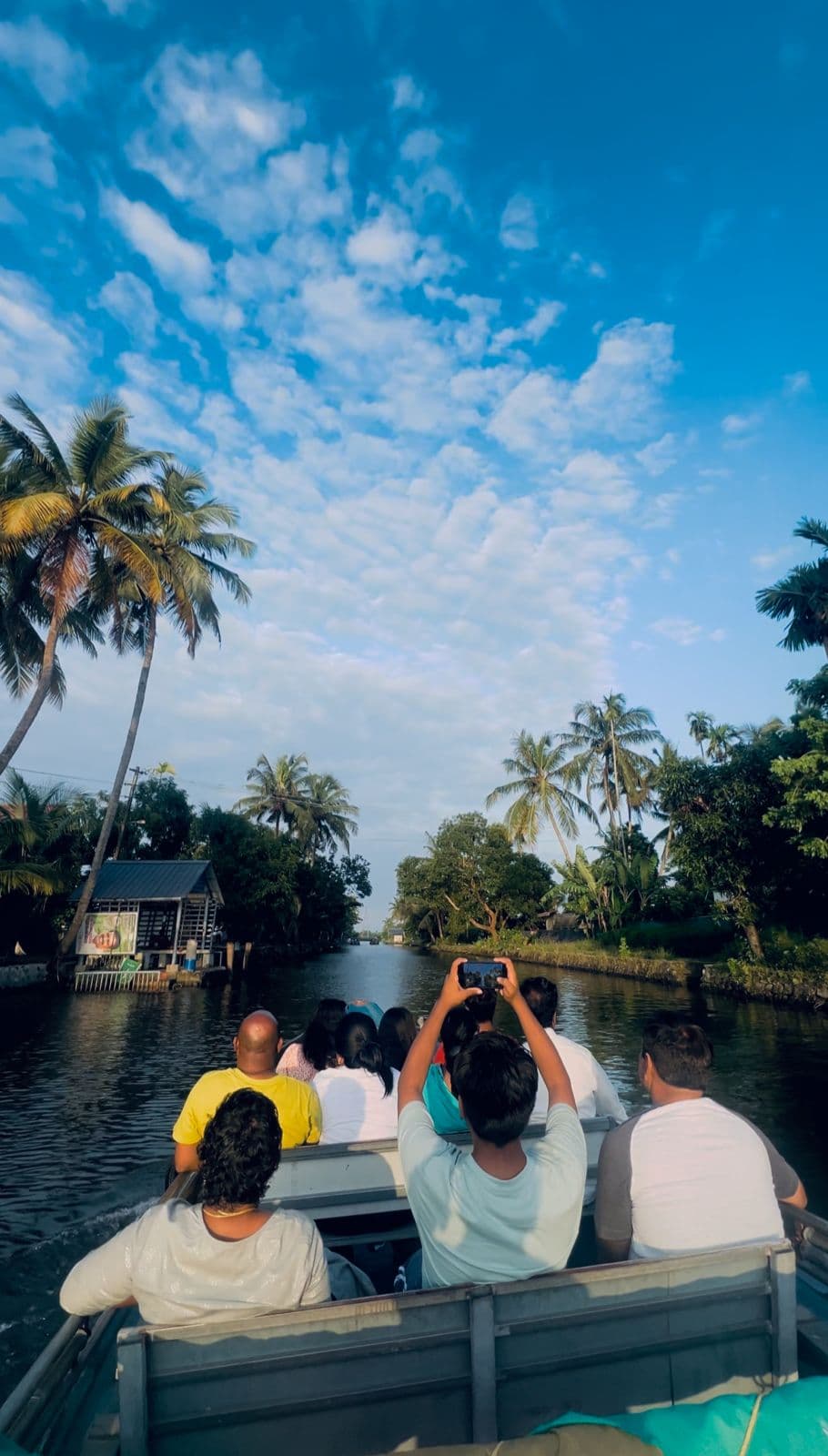 Group passengers riding under a low bridge on a village canal