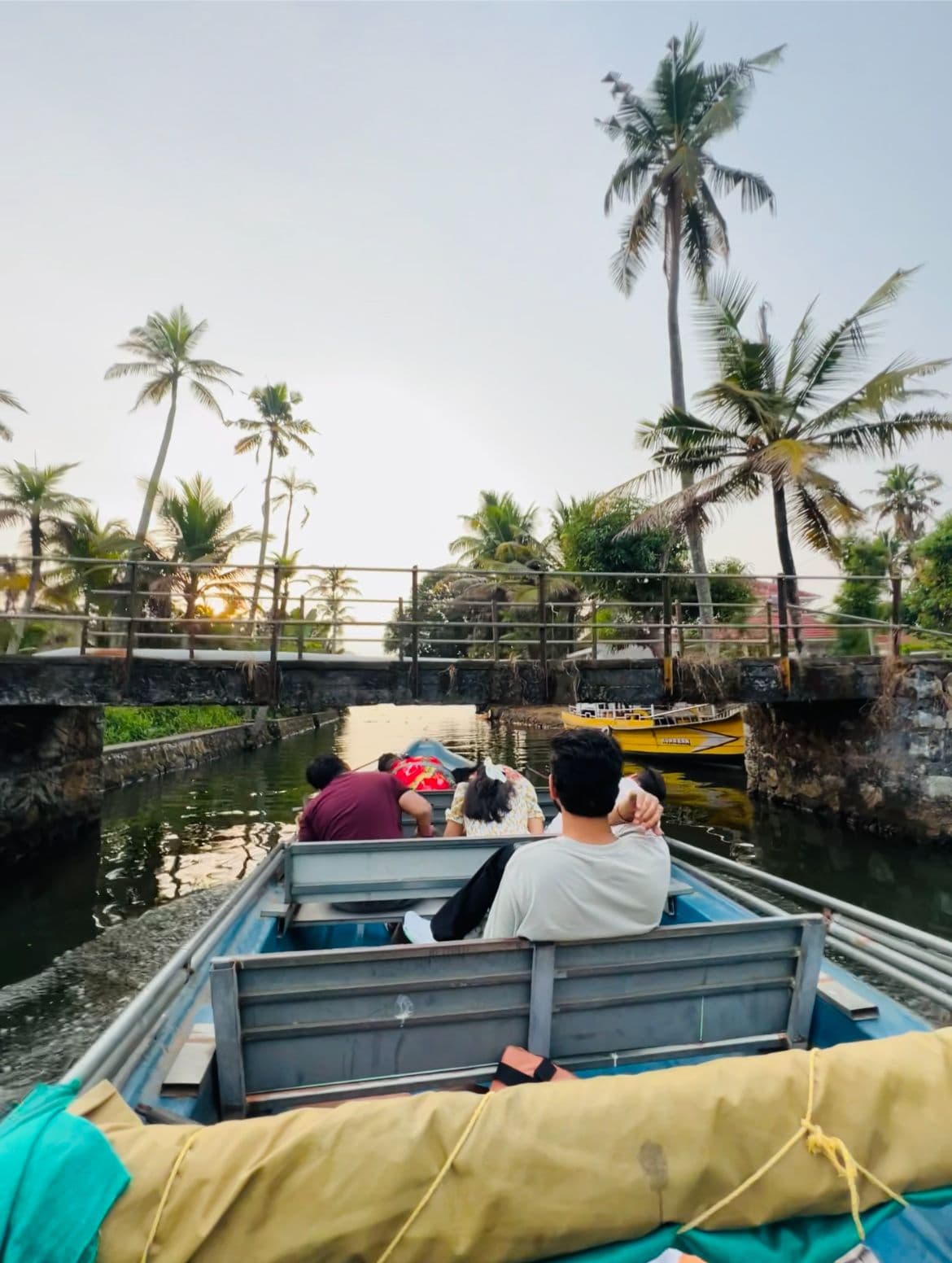Guests leaning forward in a boat passing under a bridge on the backwaters