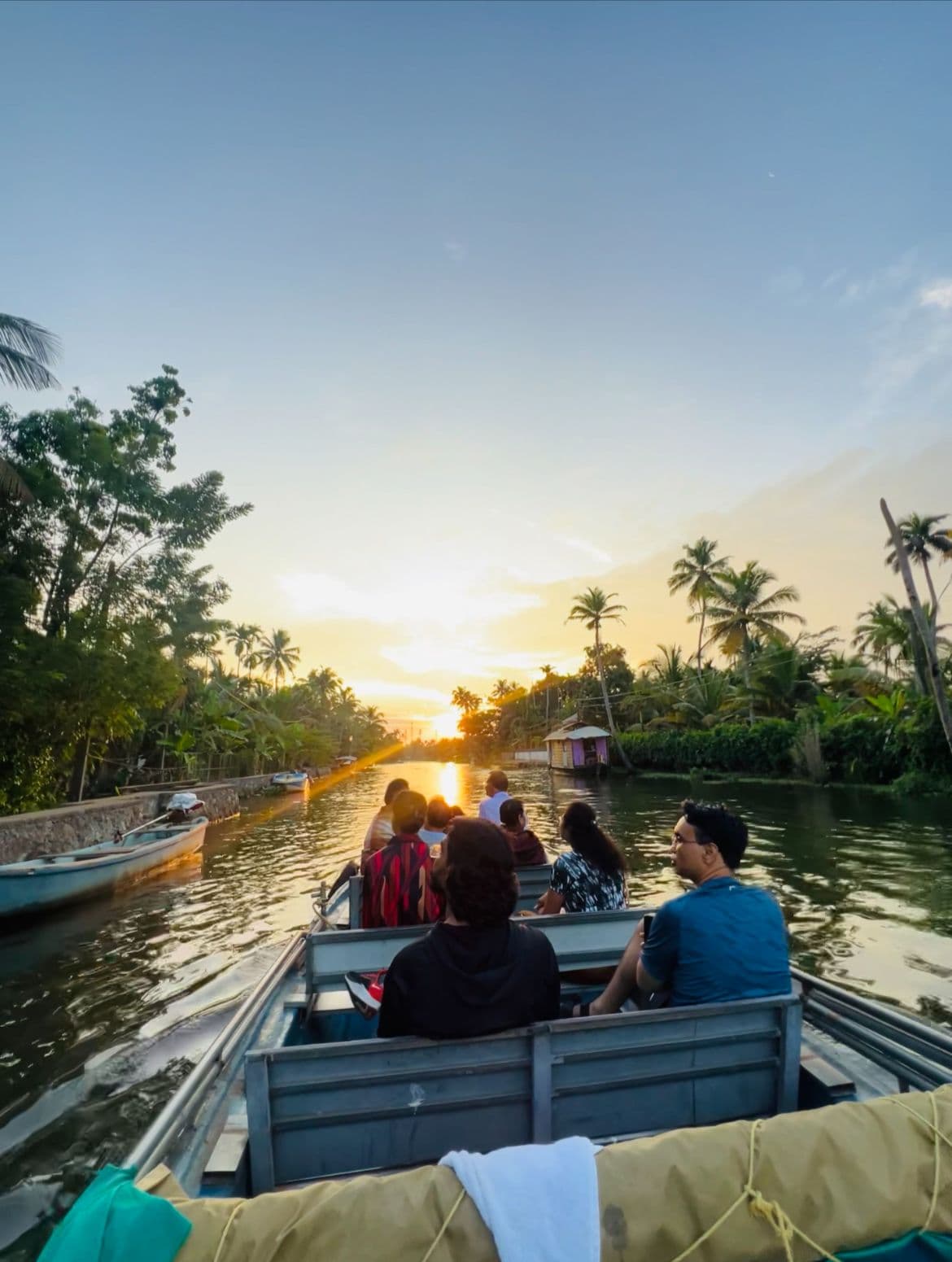 A couple smiling and making a heart shape at sunset from a boat