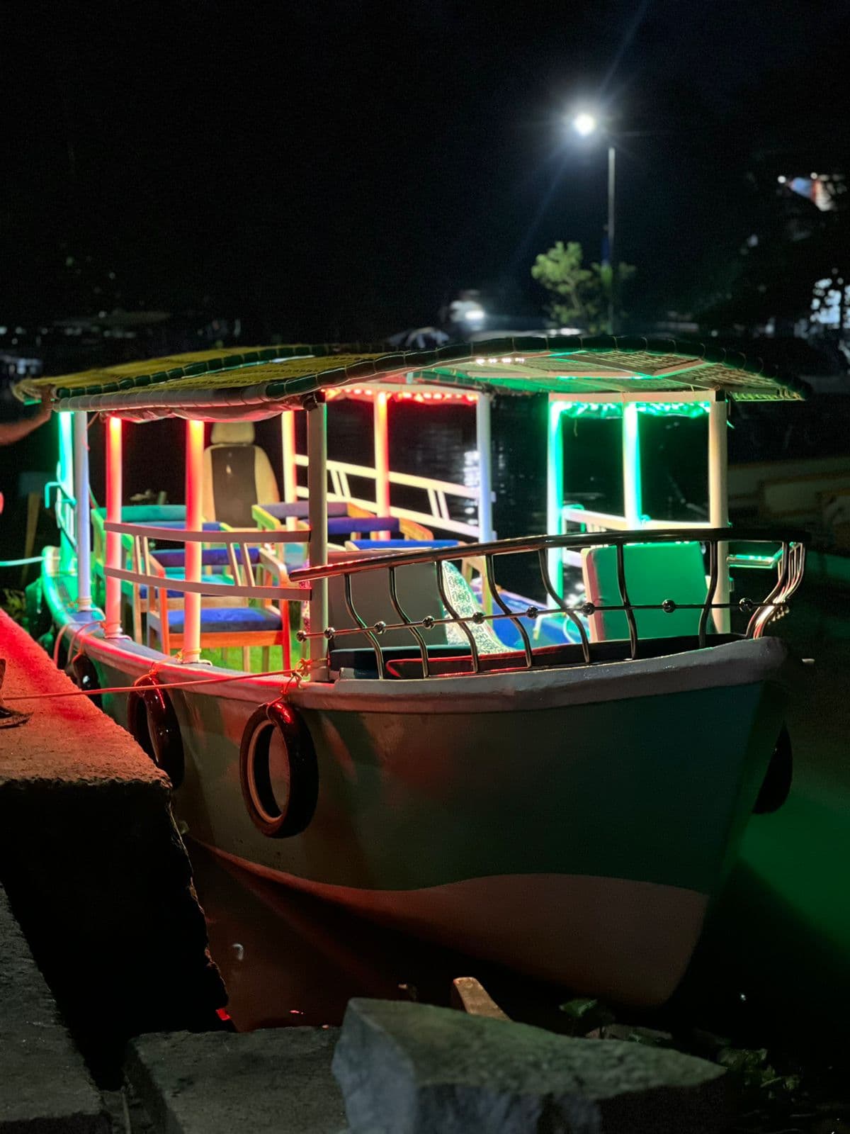 A seated group riding under the roof of a covered boat on a bright canal route