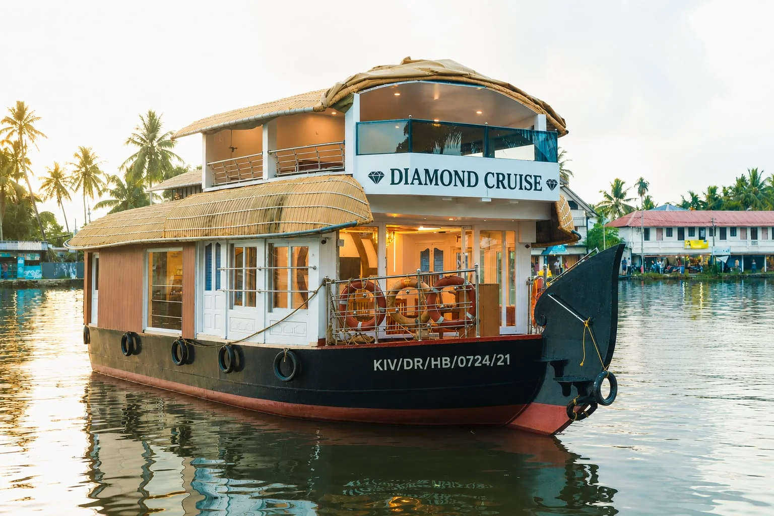 The one bedroom Deluxe houseboat Diamond Cruise on the water at dusk, with a thatched two-level roof