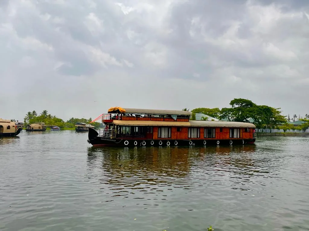 The four bedrooms Deluxe houseboat cruising across open water, with a wooden-panelled hull and an open upper deck