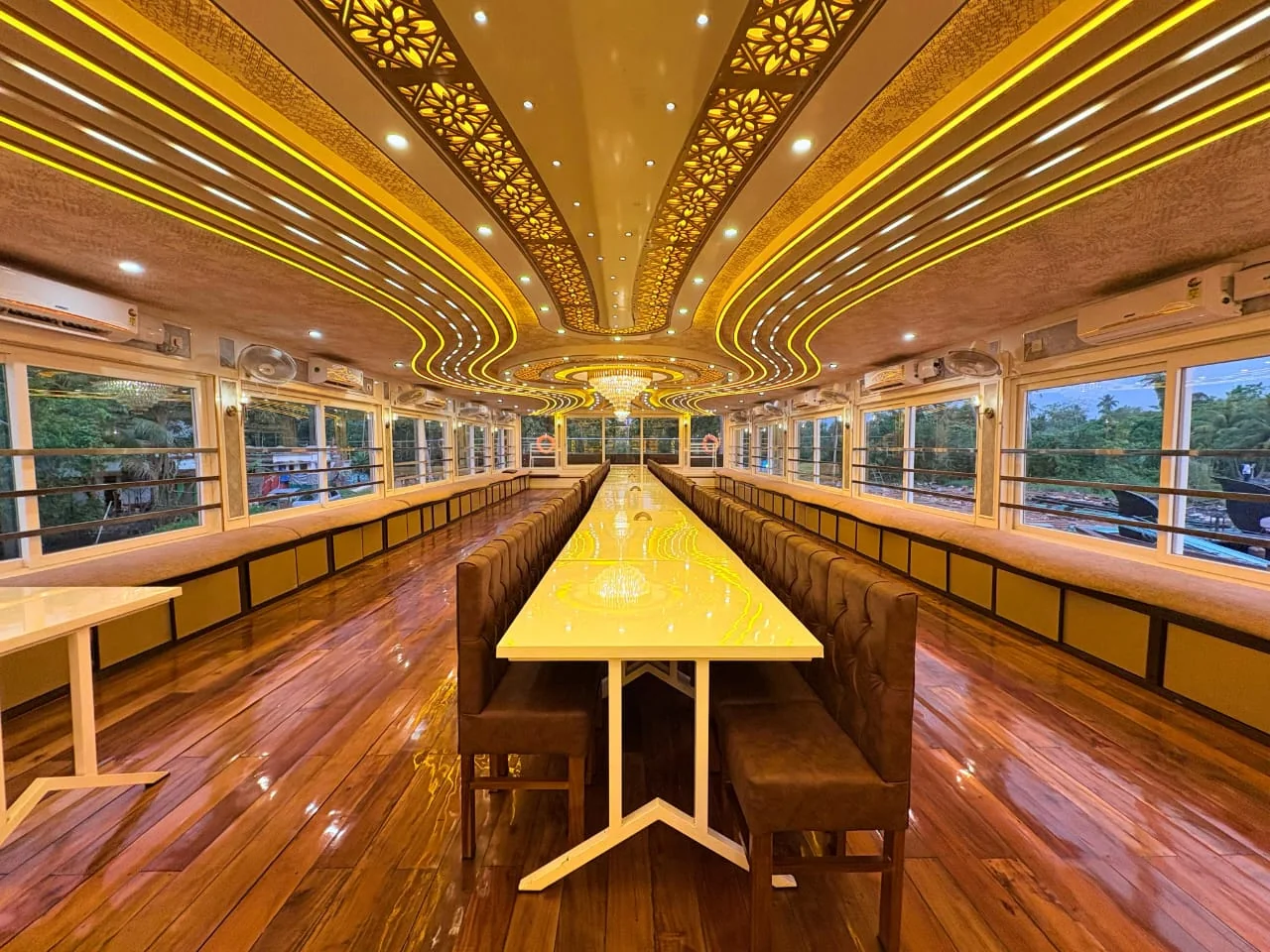 Long party dining hall with a glossy white table, brown tufted chairs and a sweeping gold-lit ceiling