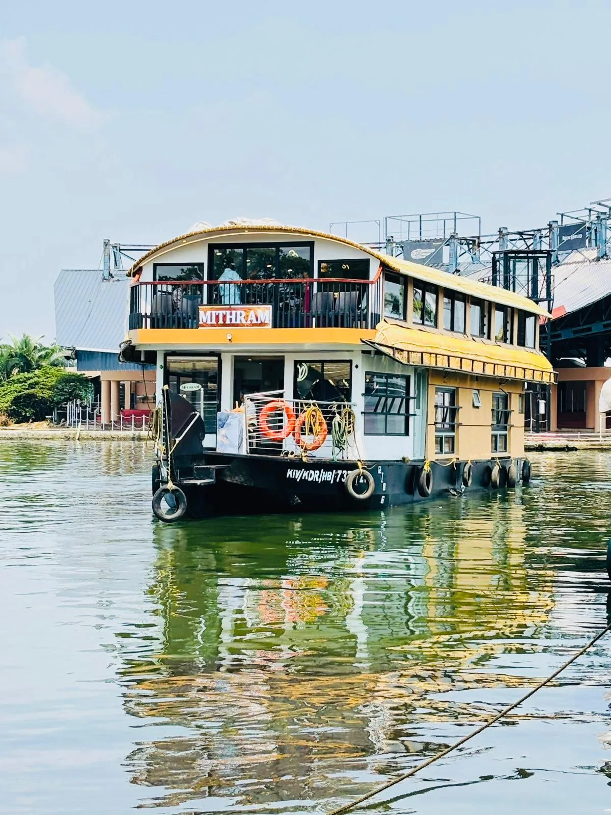 The three bedrooms Premium houseboat Mithram on the water, with a railed upper deck and a golden thatched roof