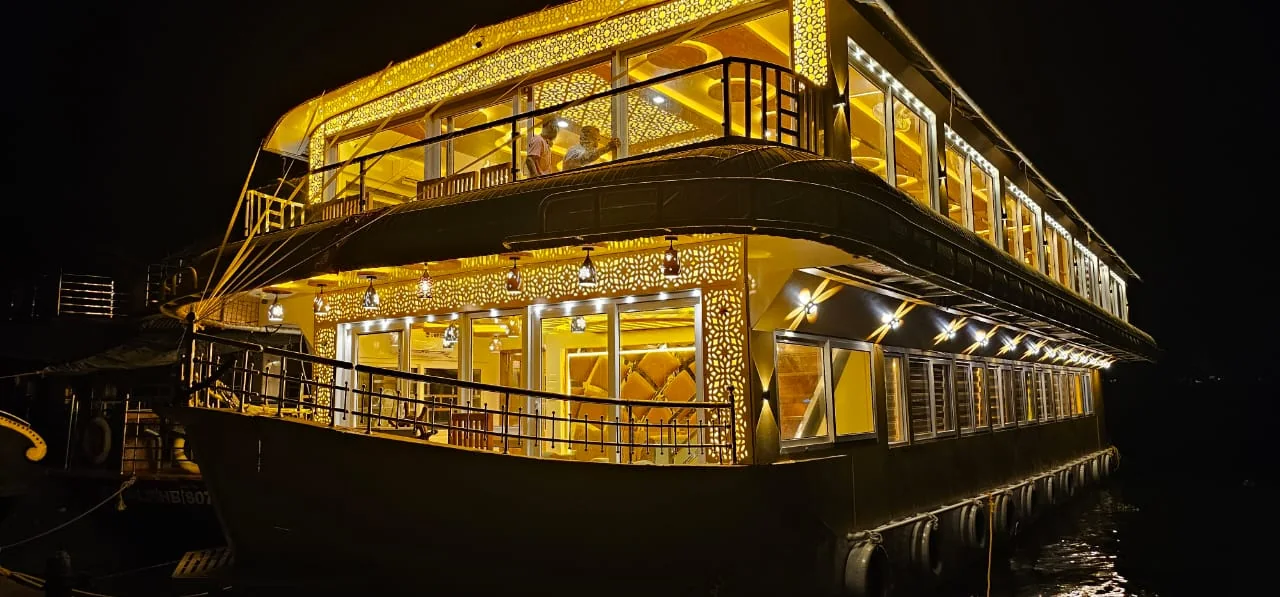 The eight bedrooms Premium houseboat lit up at night, with three glowing decks and carved lattice panels
