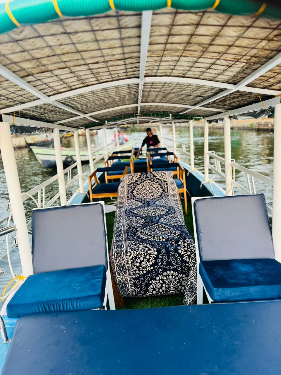 Under the canopy of a shikkara, with cushioned blue loungers and a patterned runner along the aisle