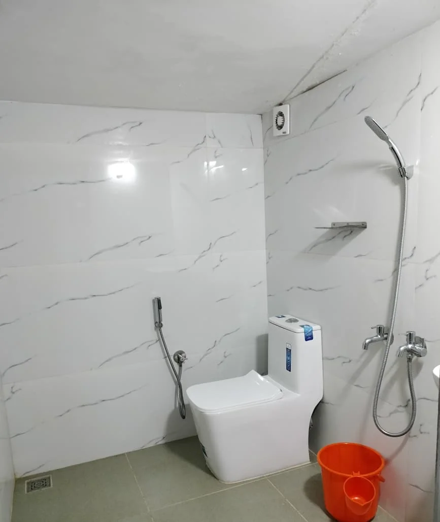 Bathroom with white marble-look tiles, a rain shower and a wall-hung toilet