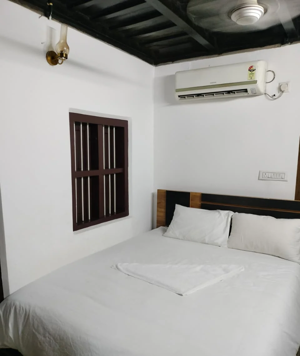 Bedroom with a double bed, a timber headboard, an air-conditioner and a dark beamed ceiling