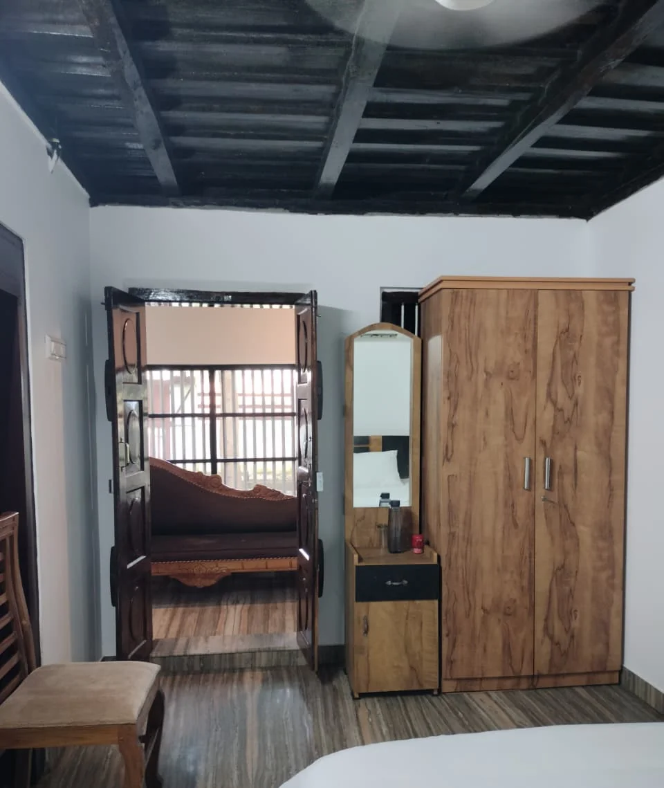 Bedroom with a dressing table, a wardrobe and a carved door opening onto a sofa beyond