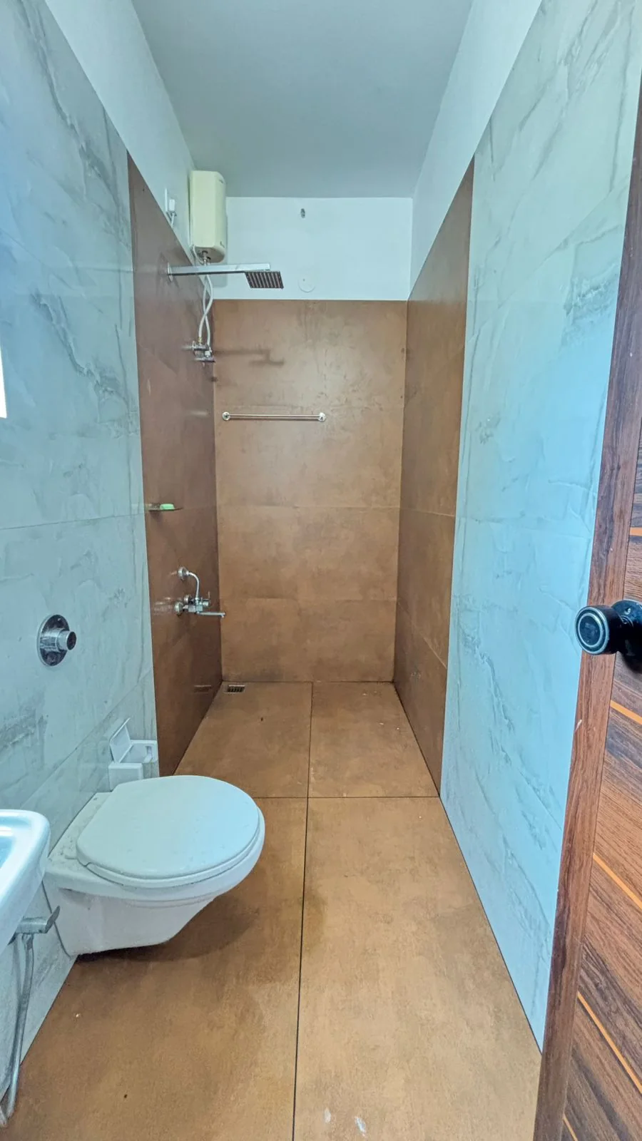 Bathroom with marble-look walls, bronze tiles and a rain shower